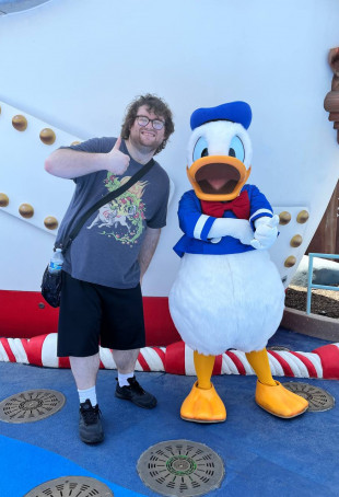 Terin giving a thumbs up while standing next to a person in a Donald Duck costume.