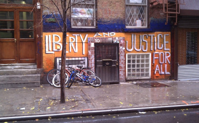 Exterior of building with a mural painted on it that reads Liberty and Justice for All